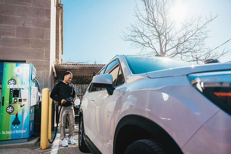 a man charging his car at an EV charging station
