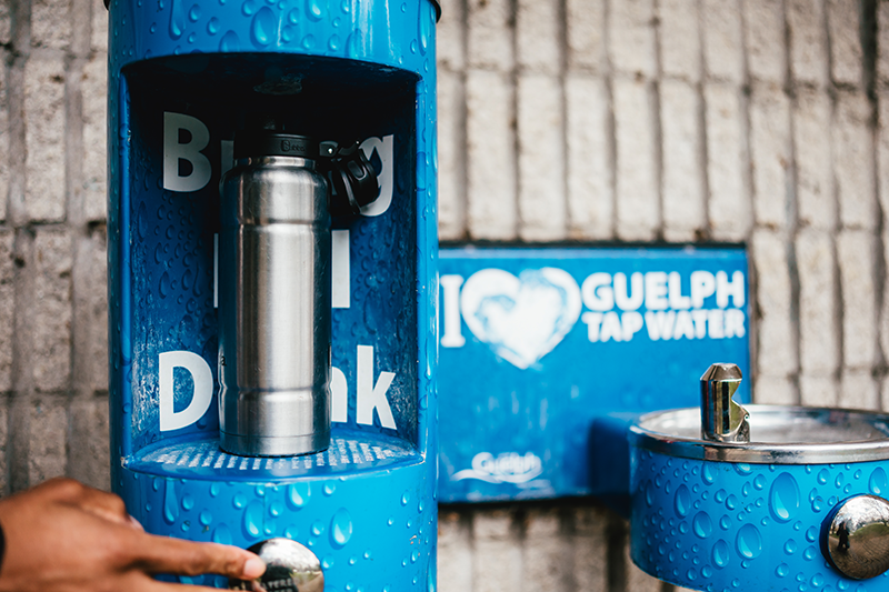 A water fountain with since above it that says" I love Guelph tap water" next to a "Bring, fill drink" water bottle fill station