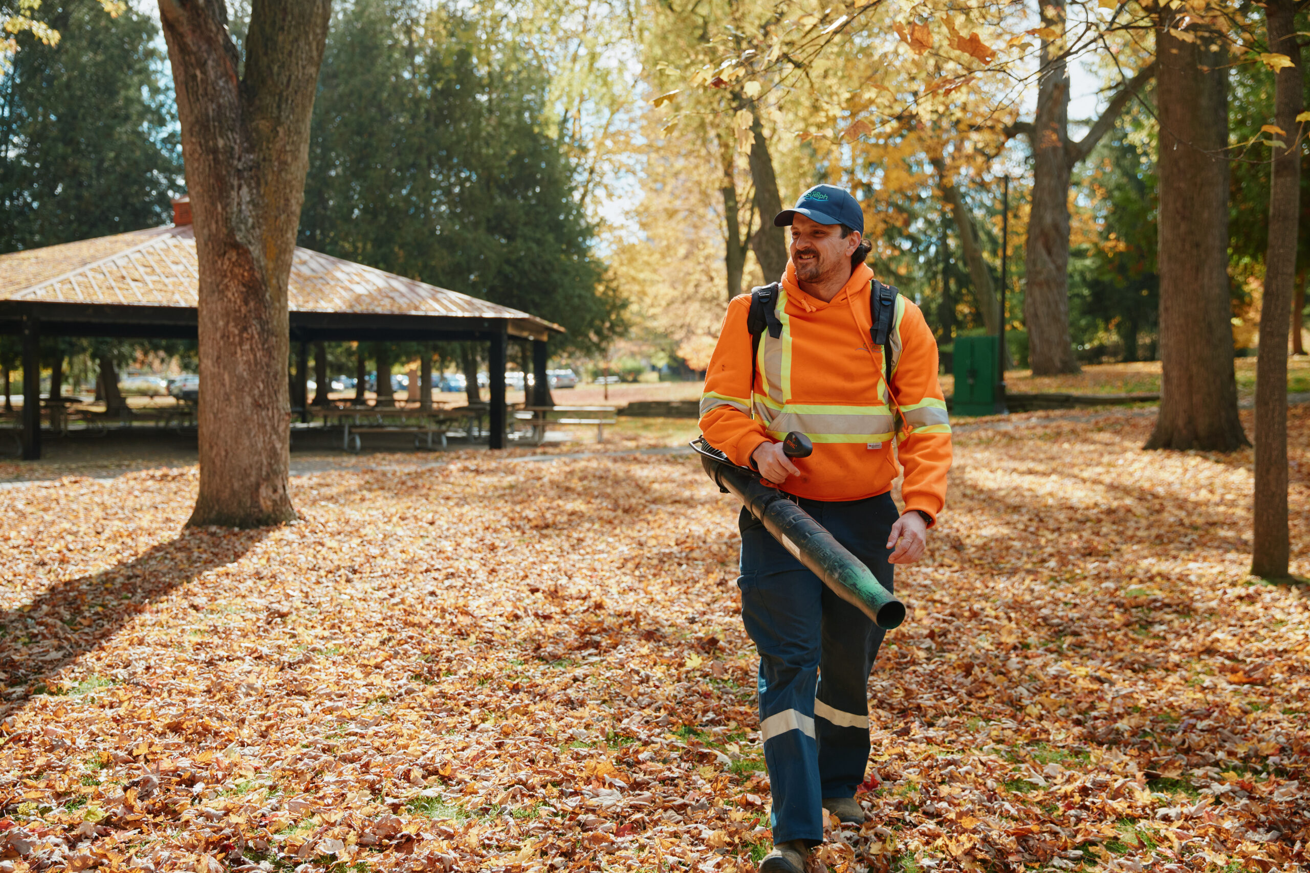 Employee with leaf blower walking through forest